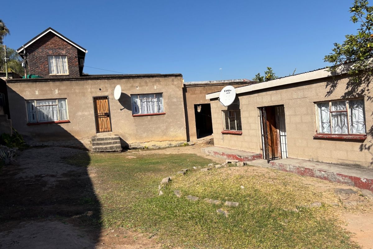 Rear view of the property showing multiple building sections, weathered plaster finishes, metal window frames, and a central courtyard area.