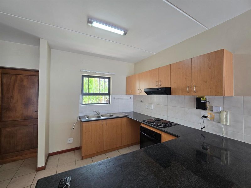 A functional kitchen featuring laminate cabinetry, granite countertops, a double bowl sink, and built-in electric cooking appliances with a tiled backsplash.