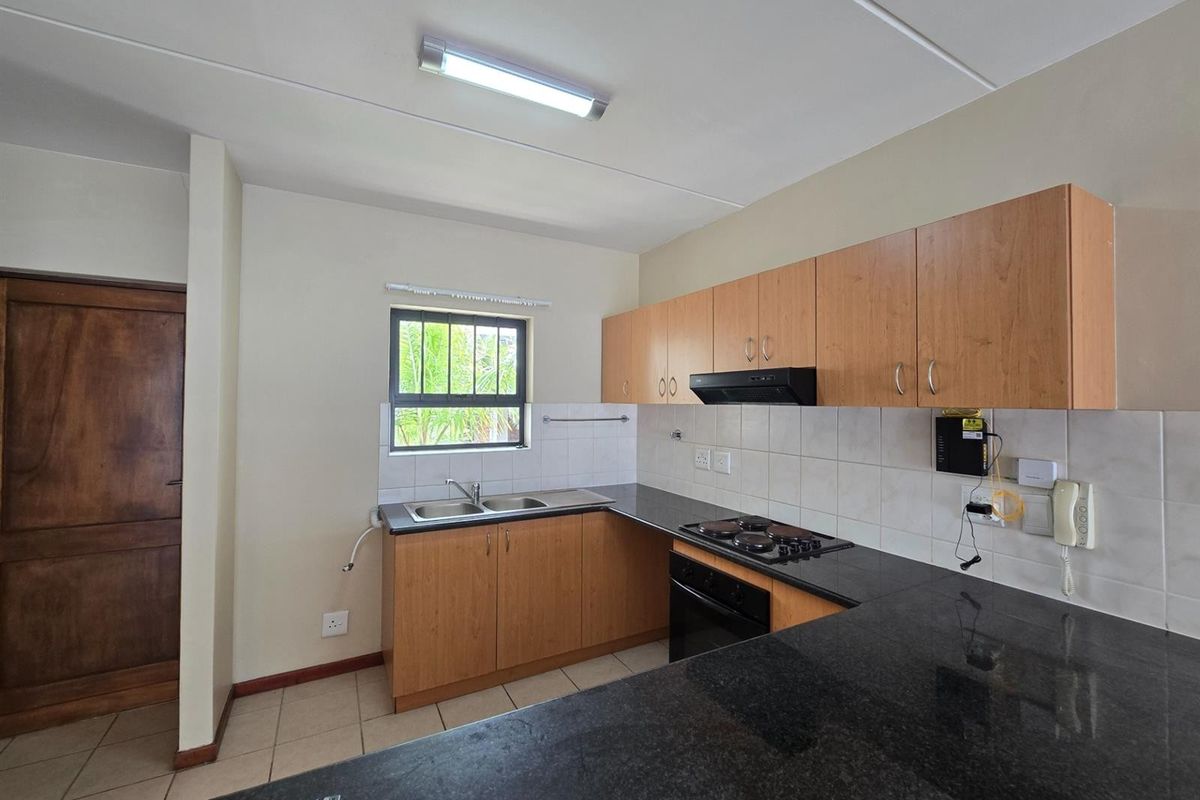 A functional kitchen featuring laminate cabinetry, granite countertops, a double bowl sink, and built-in electric cooking appliances with a tiled backsplash.