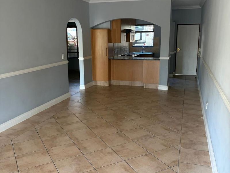 An open-plan living and kitchen area featuring tiled flooring, arched transitions, and built-in kitchen cabinetry with integrated appliances.