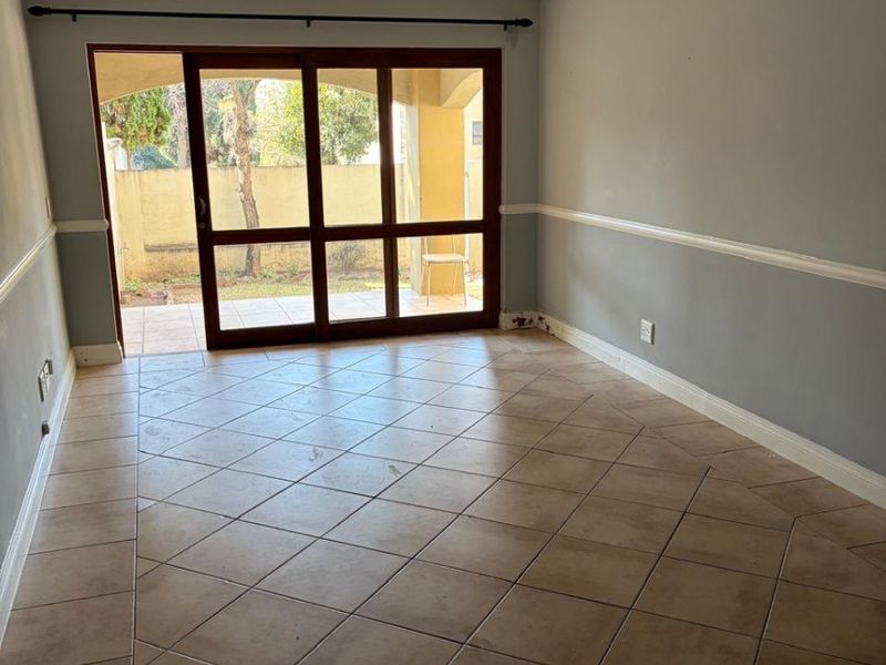 An empty living room featuring tiled flooring, crown molding, chair rail, and a large sliding glass door providing access to an outdoor patio area.