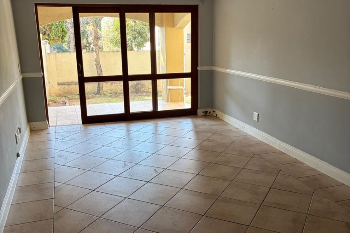 An empty living room featuring tiled flooring, crown molding, chair rail, and a large sliding glass door providing access to an outdoor patio area.