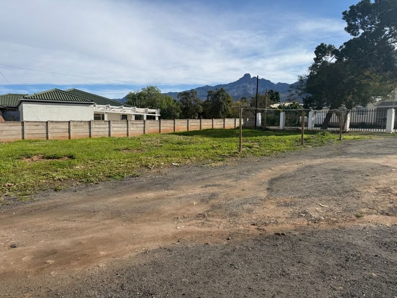 A view of a vacant rear yard area featuring a precast concrete boundary wall and mountain views in the background.