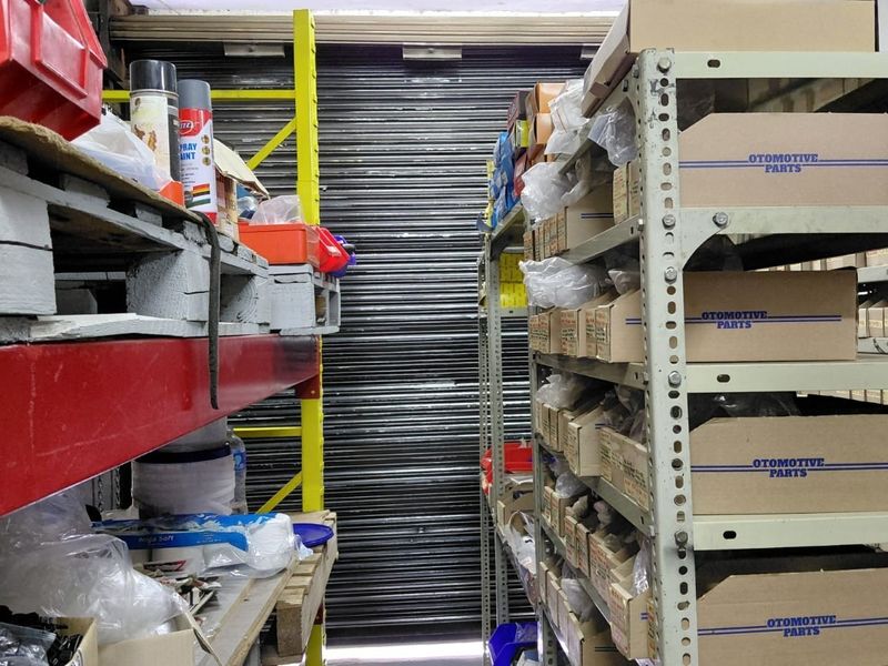 A commercial utility or storage space featuring heavy-duty industrial metal shelving units and a secure roller shutter door.