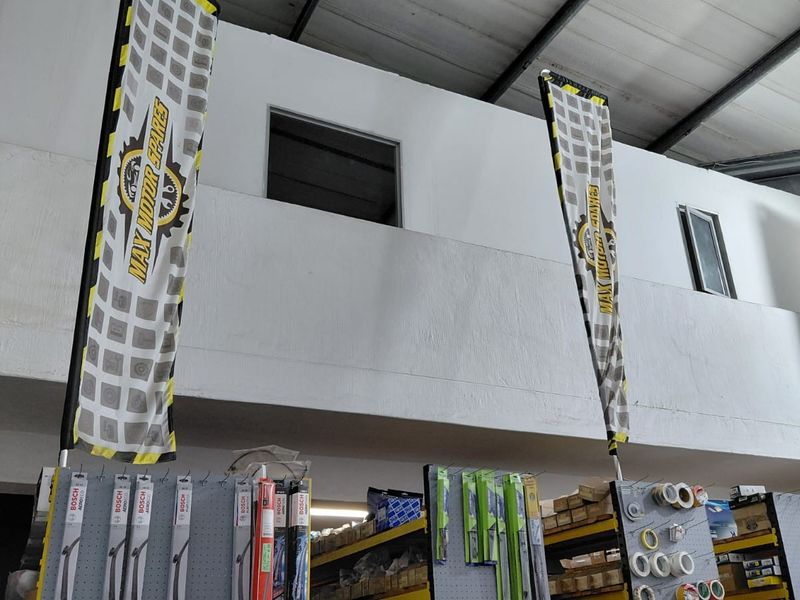 Interior view of a commercial warehouse space featuring a mezzanine level with exposed steel roof structure and industrial windows.