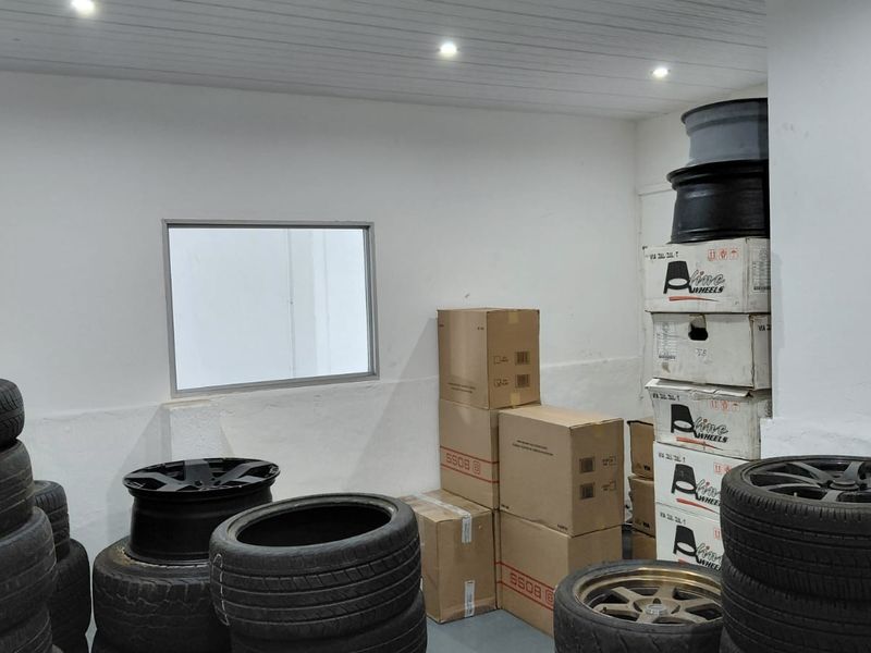 A functional utility or storage space featuring recessed ceiling lighting and a fixed window, currently utilized for inventory storage.