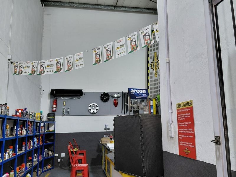 Commercial utility space featuring high ceilings, industrial metal shelving, and wall-mounted air conditioning unit, currently utilized for retail storage and display.