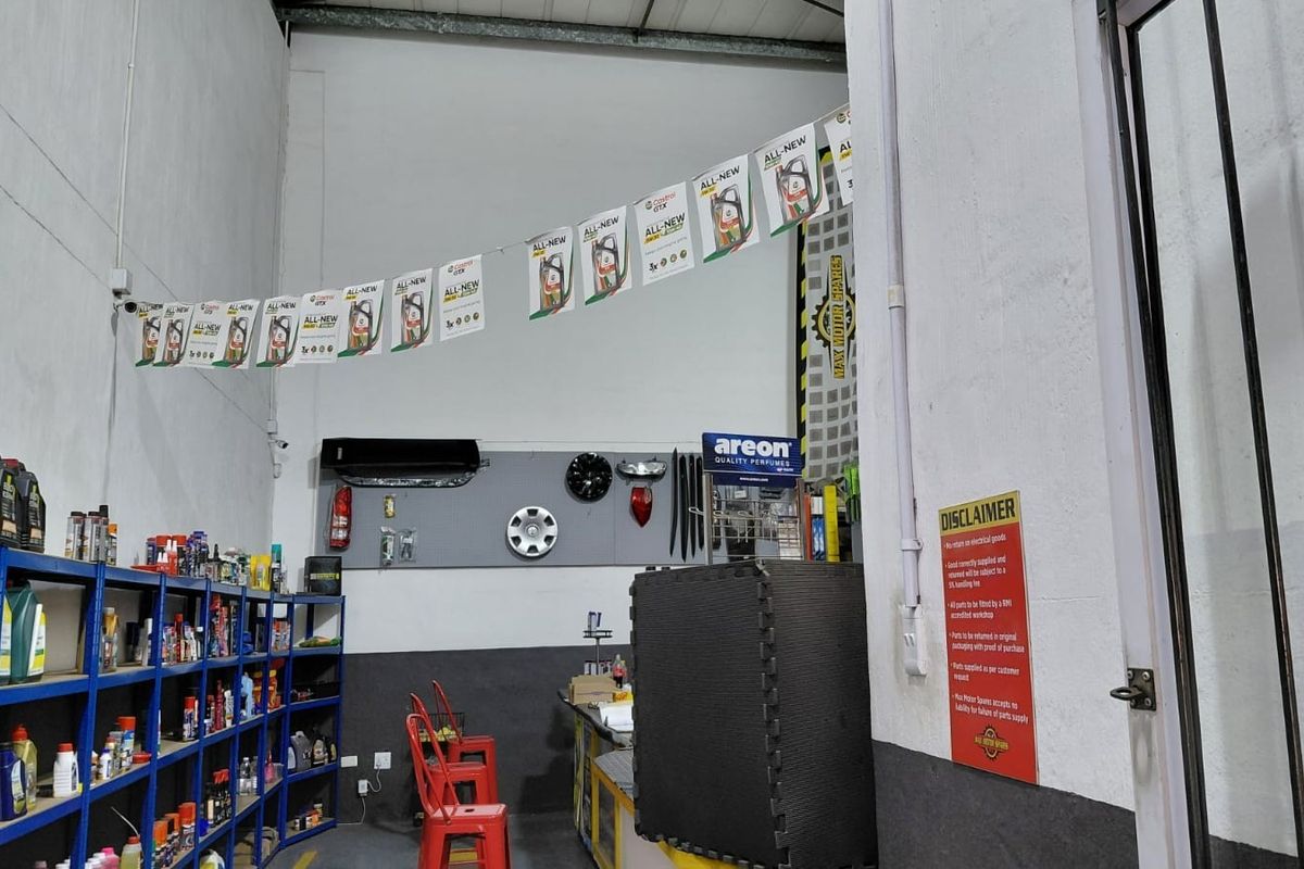 Commercial utility space featuring high ceilings, industrial metal shelving, and wall-mounted air conditioning unit, currently utilized for retail storage and display.