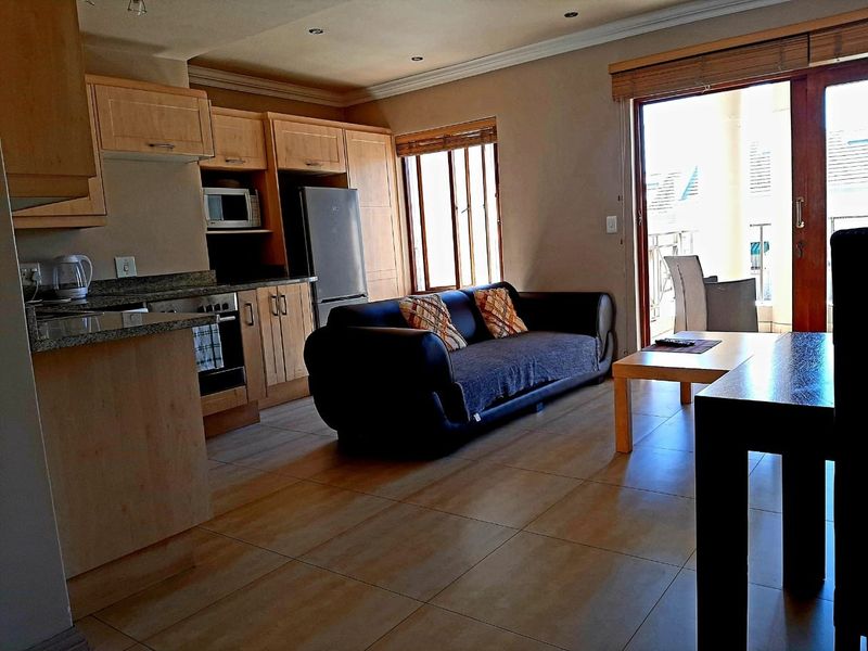Open-plan living area featuring a functional kitchen with granite countertops, built-in appliances, and direct access to a balcony through sliding glass doors.