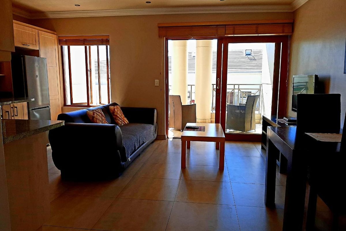 Open-plan living area featuring tiled floors, integrated kitchen cabinetry, and sliding glass doors leading to a private balcony.