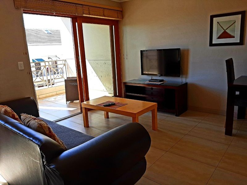 A living room featuring tiled flooring and large sliding glass doors that provide direct access to an outdoor balcony area.