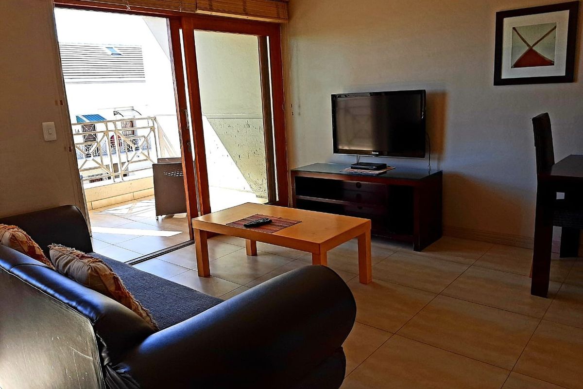 A living room featuring tiled flooring and large sliding glass doors that provide direct access to an outdoor balcony area.