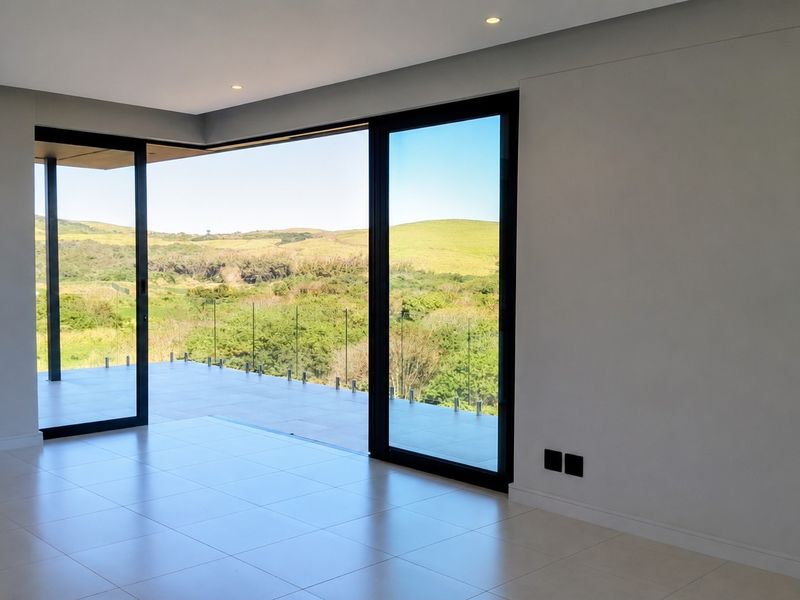 Spacious, modern living area featuring large sliding glass doors that open onto a covered patio with scenic landscape views.