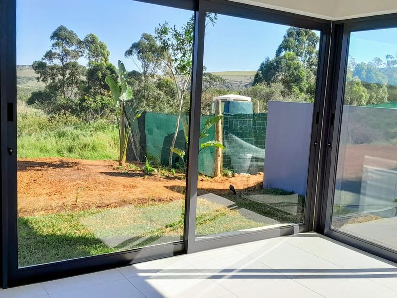 Bright, empty living space featuring large sliding glass doors that provide seamless access to the outdoor garden area.
