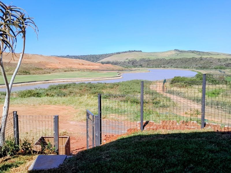 Scenic view overlooking a natural landscape, river, and golf course fairway, framed by perimeter wire mesh fencing.