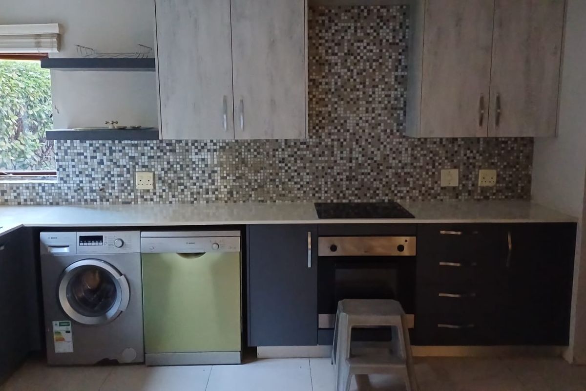 Modern kitchen featuring two-tone cabinetry, mosaic tile backsplash, integrated appliances, and a built-in oven and hob setup.