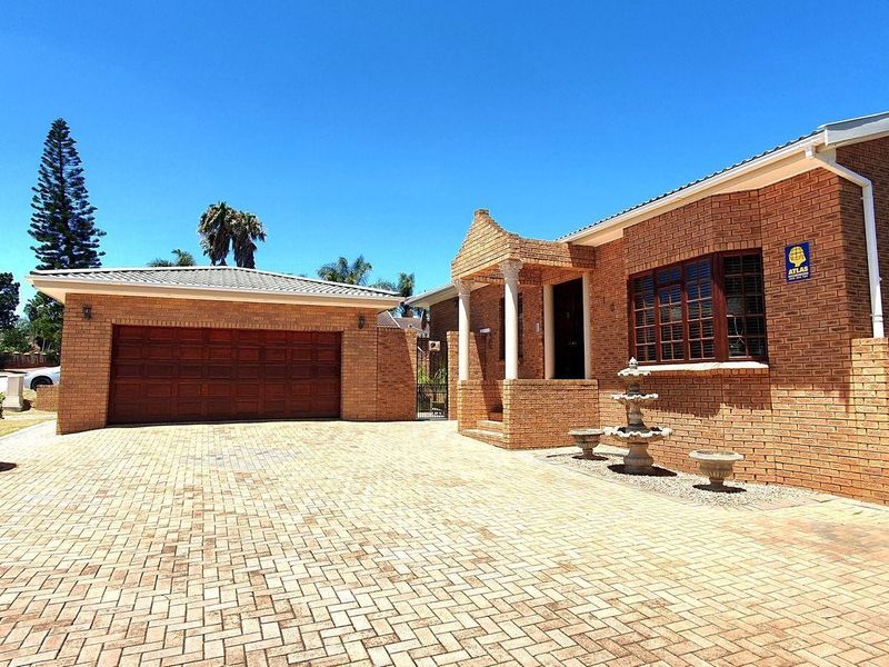 Front exterior view of a brick house featuring a paved driveway, double garage, and a covered entrance porch with a decorative fountain.