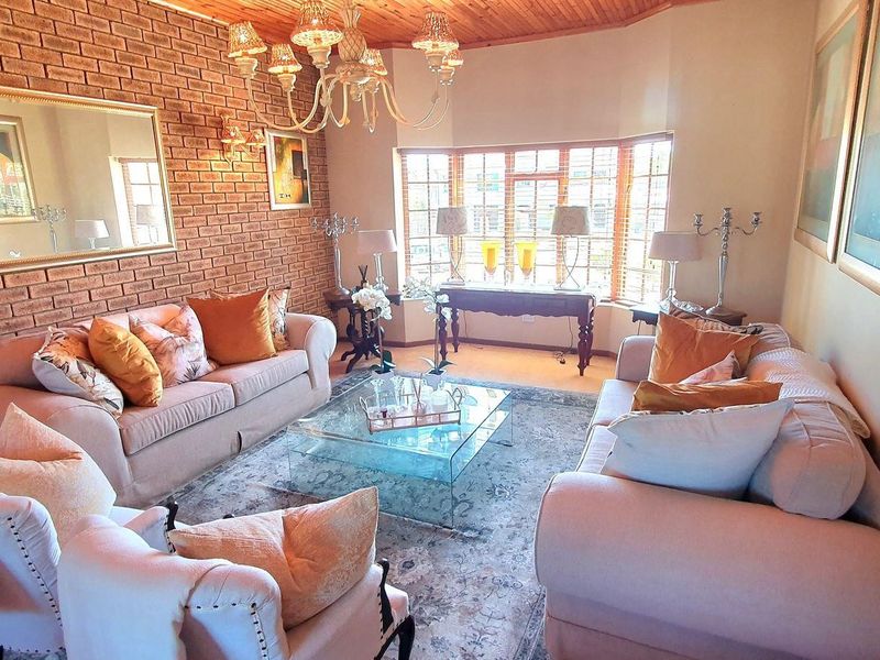 A cozy living room featuring an exposed brick wall, timber ceiling, and a large bay window that allows for ample natural light.