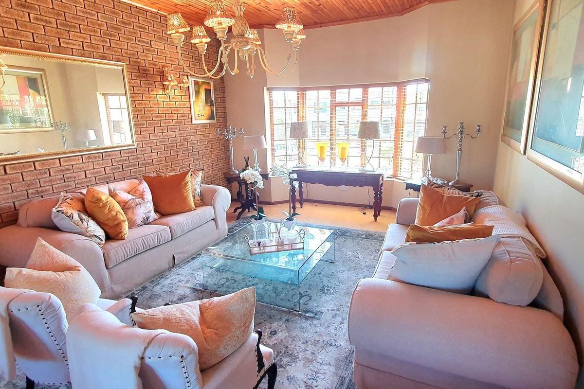 A cozy living room featuring an exposed brick wall, timber ceiling, and a large bay window that allows for ample natural light.