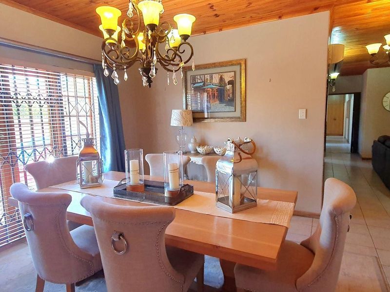 Dining room featuring a timber ceiling, tiled flooring, and a decorative chandelier, with large windows fitted with security bars.