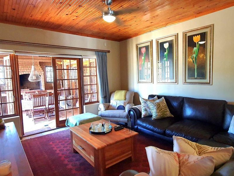 A cozy living room featuring a warm timber tongue and groove ceiling, ceiling fan, and sliding glass doors providing access to an outdoor patio area.