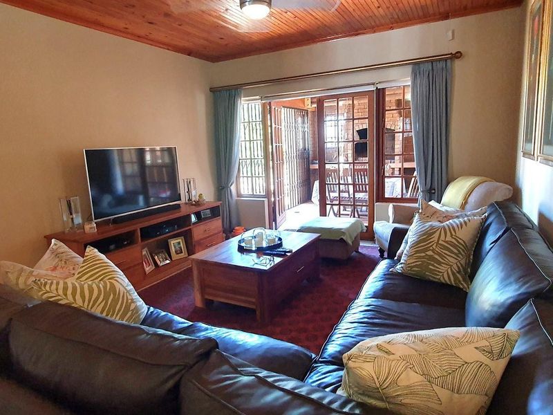 A comfortable living room featuring a warm timber tongue and groove ceiling and sliding glass doors that open onto an outdoor patio area.