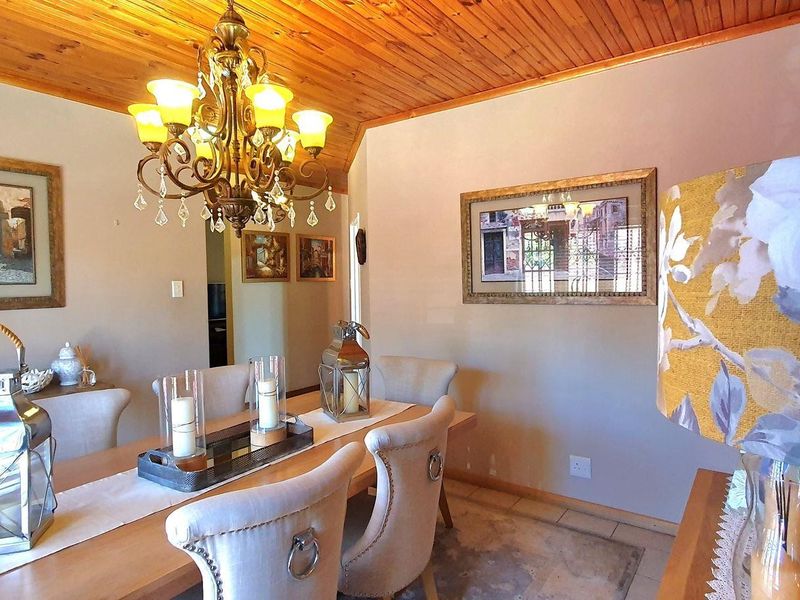 A dining room featuring a vaulted timber-clad ceiling, tiled flooring, and an ornate chandelier, providing a warm and traditional atmosphere.