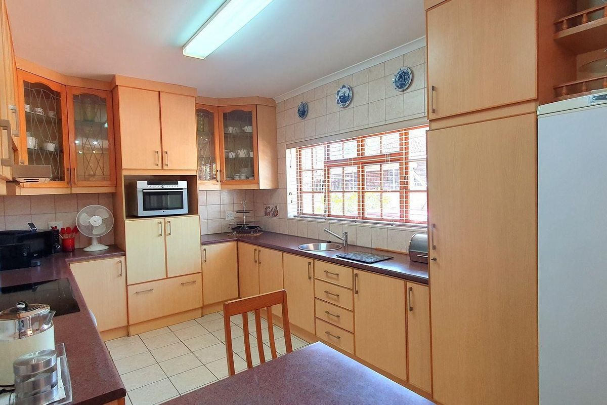A functional kitchen featuring light wood-tone cabinetry, laminate countertops, tiled backsplash, and ceramic flooring with ample storage space.