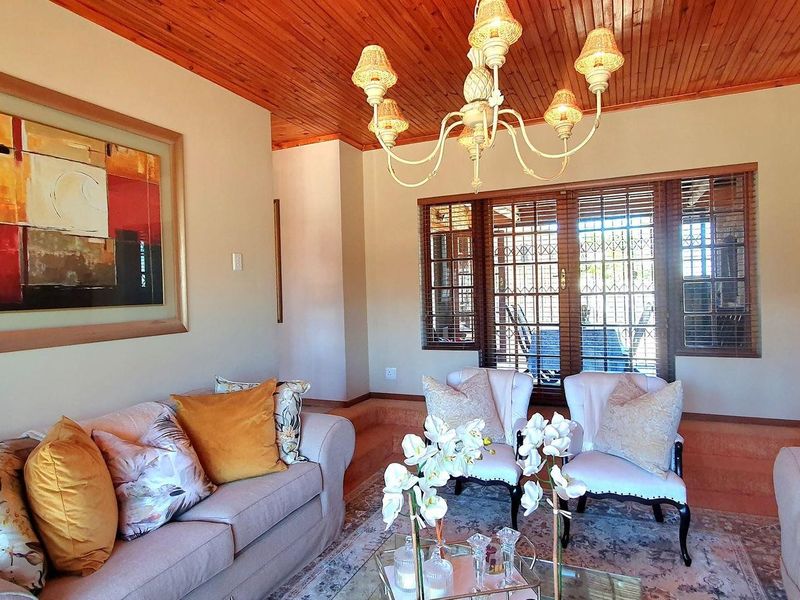 A cozy living room featuring a warm timber ceiling, exposed brick wall, and a classic chandelier, providing a comfortable and inviting atmosphere.