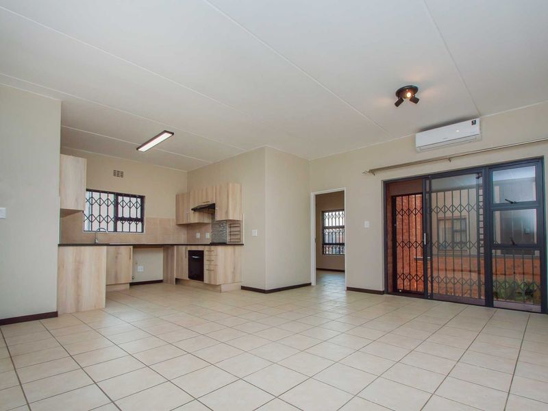 Spacious open-plan living area featuring tiled floors, a modern kitchen with built-in cabinetry, and a sliding door leading to the exterior.