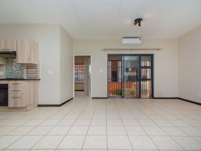 Spacious open-plan living area featuring tiled floors, an integrated kitchen with built-in oven and extractor, and direct access to an outdoor patio area.
