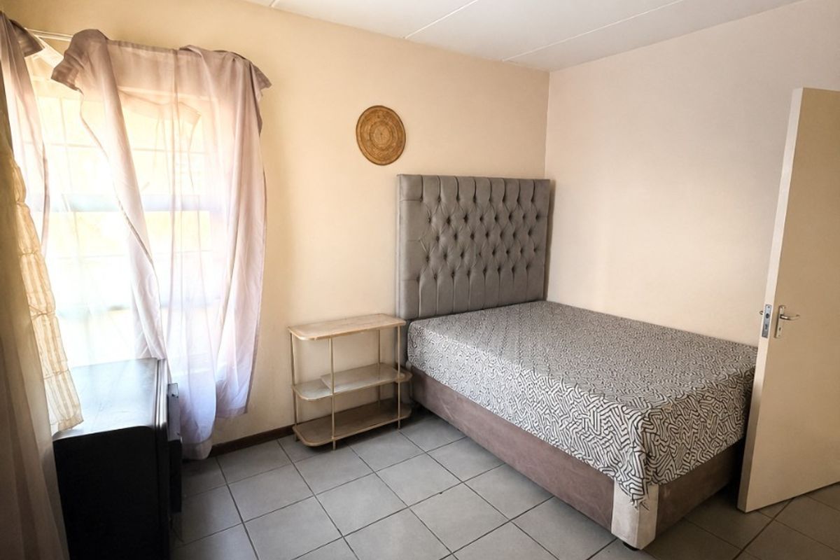 A functional bedroom featuring tiled flooring, a standard window, and a ceiling light fixture, offering a neutral space ready for personalization.