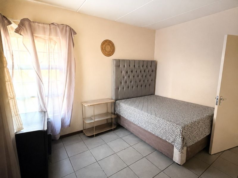 A functional bedroom featuring tiled flooring, a standard window, and a ceiling light fixture, offering a neutral space ready for personalization.