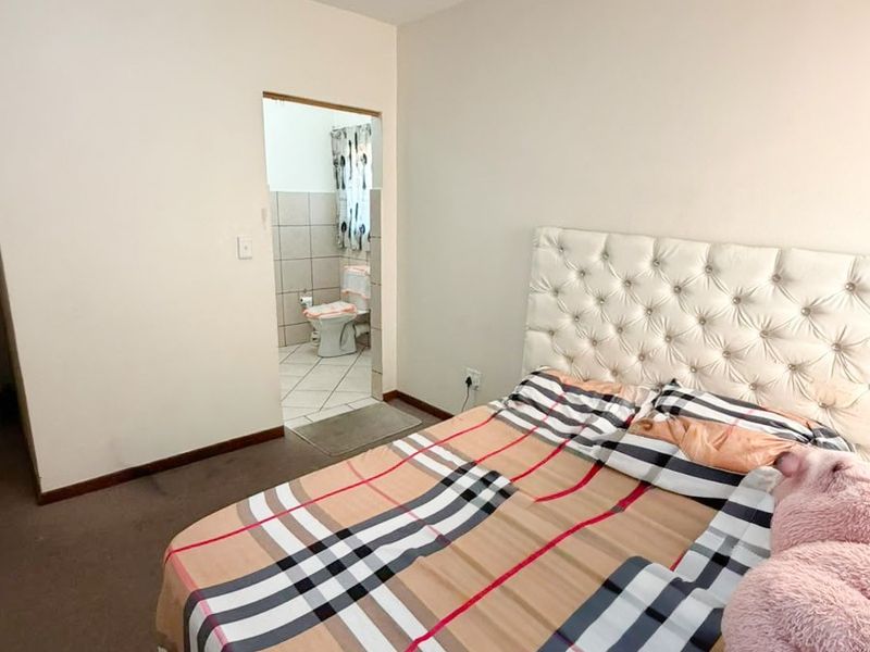 A bedroom featuring carpeted flooring and an adjoining en-suite bathroom with tiled finishes.