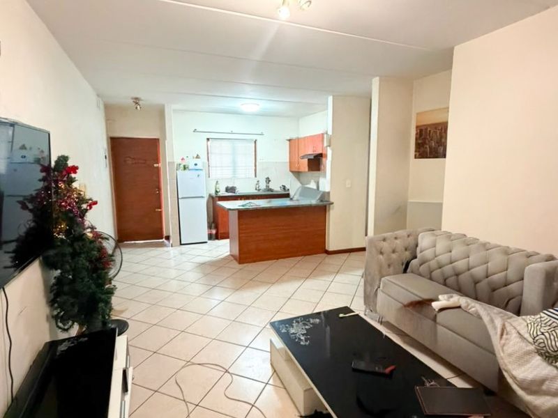 Open-plan living area featuring tiled flooring and a functional kitchen with built-in cabinetry and an island, providing a versatile space for daily living.