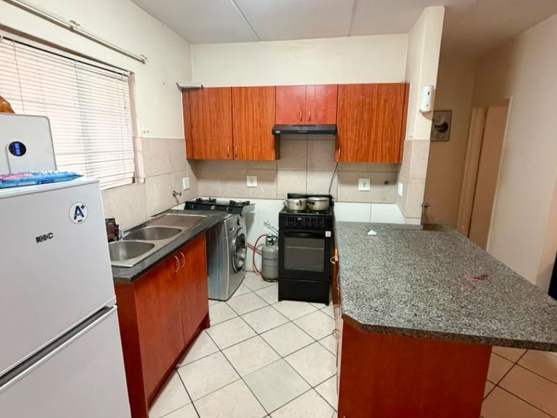Functional kitchen featuring wood-finish cabinetry, granite countertops, a double sink, and a tiled backsplash, providing a practical workspace for daily cooking.