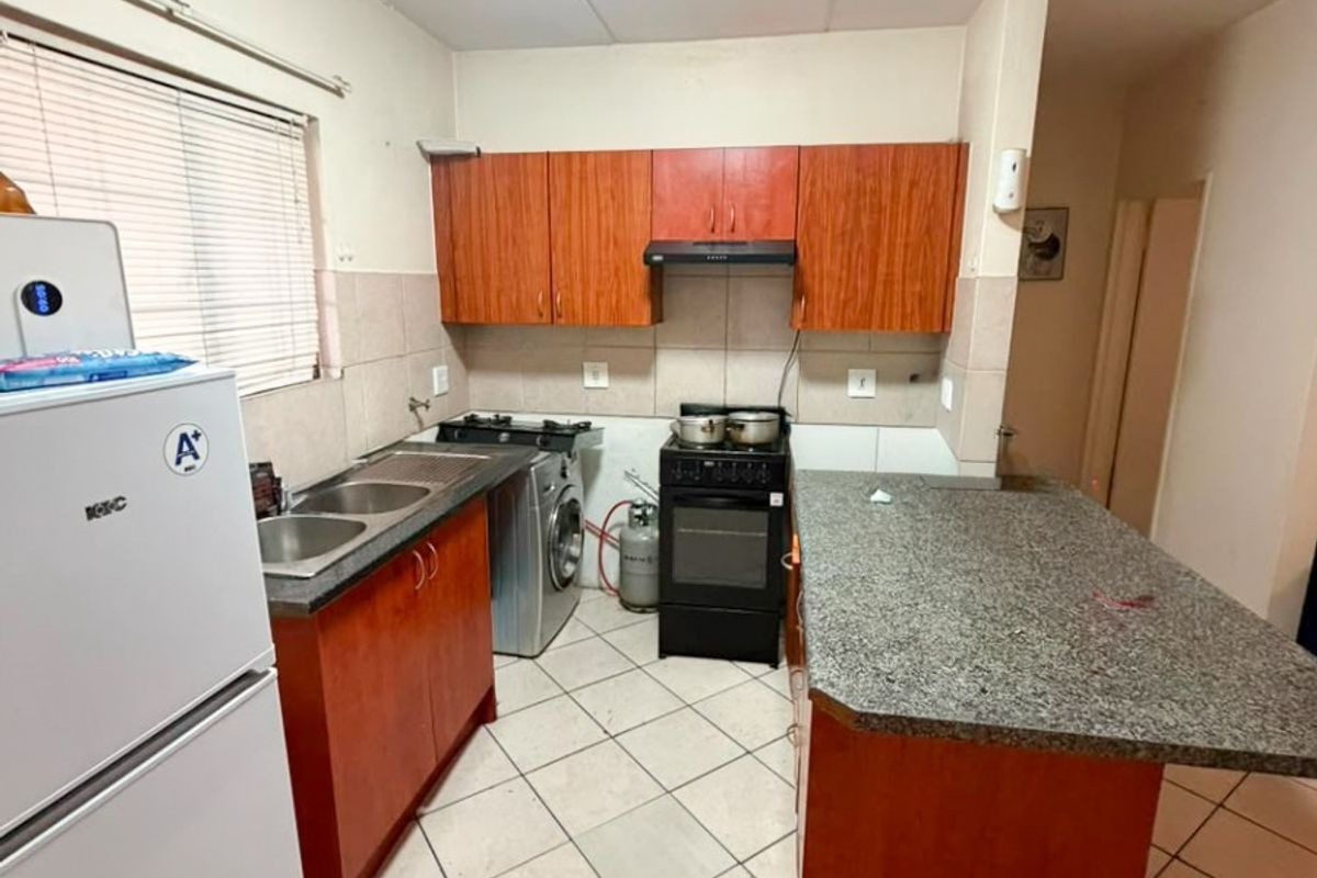 Functional kitchen featuring wood-finish cabinetry, granite countertops, a double sink, and a tiled backsplash, providing a practical workspace for daily cooking.