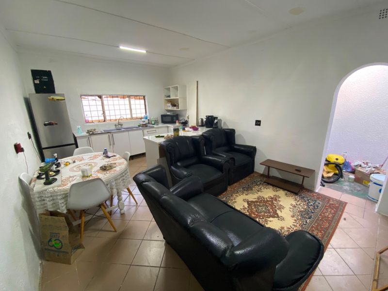 Open-plan living and kitchen area featuring tiled flooring, functional cabinetry, and an arched entryway leading to an adjacent utility space.