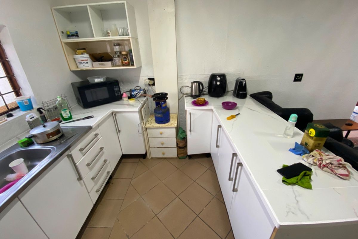 A compact kitchen featuring white cabinetry, stone countertops, and tiled flooring, requiring minor finishing touches to complete the installation.