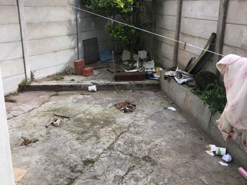 A small, paved rear courtyard area enclosed by precast concrete boundary walls, requiring maintenance and landscaping to improve its overall condition and utility.