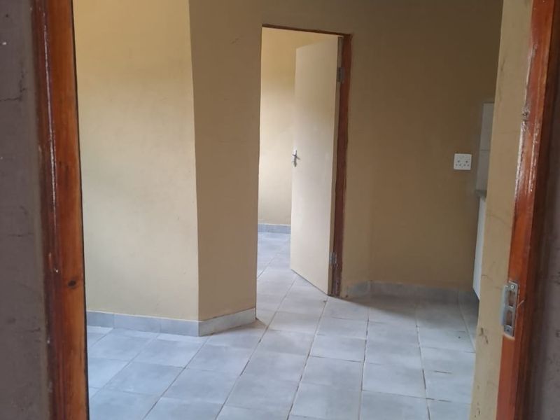 An empty living area featuring tiled flooring and neutral wall paint, providing a blank canvas for interior design and personalization.