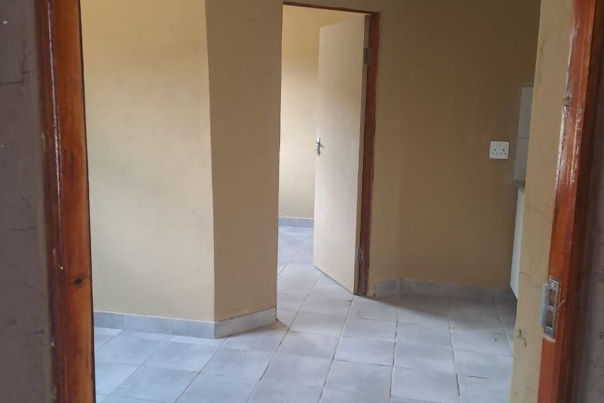 An empty living area featuring tiled flooring and neutral wall paint, providing a blank canvas for interior design and personalization.