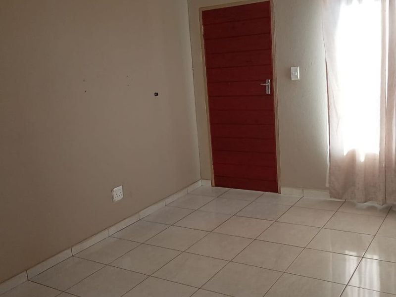 An empty bedroom featuring neutral wall paint, tiled flooring, and a single internal door, providing a blank canvas for personalization.