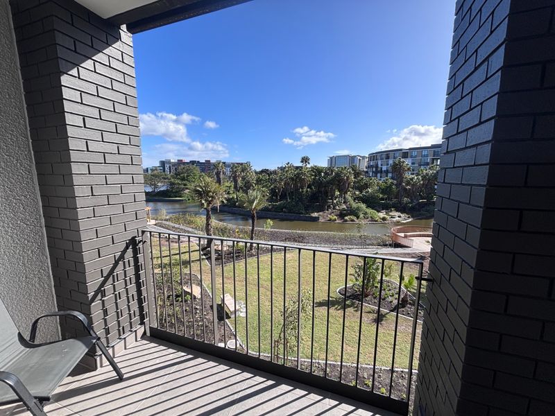 A private balcony featuring brick pillars and a metal balustrade, offering scenic views over the landscaped garden and water feature.