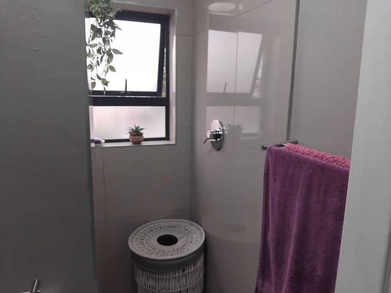 A compact bathroom featuring modern wall tiling, a chrome shower mixer, and a functional top-hung window for natural light and ventilation.