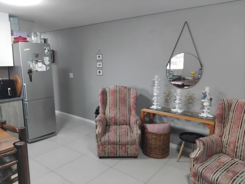 Open plan living area featuring neutral wall tones and tiled flooring, seamlessly connecting to a functional kitchen space.