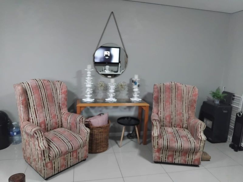 A living room area featuring neutral wall tones and tiled flooring, providing a blank canvas for potential interior design updates.