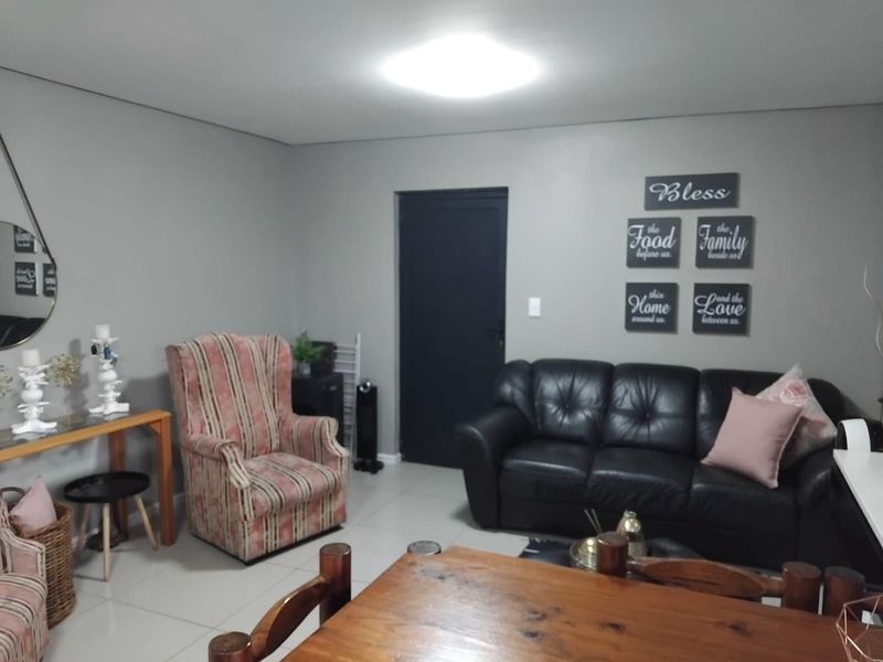 A living room area featuring neutral grey walls, tiled flooring, and a central ceiling light fixture.