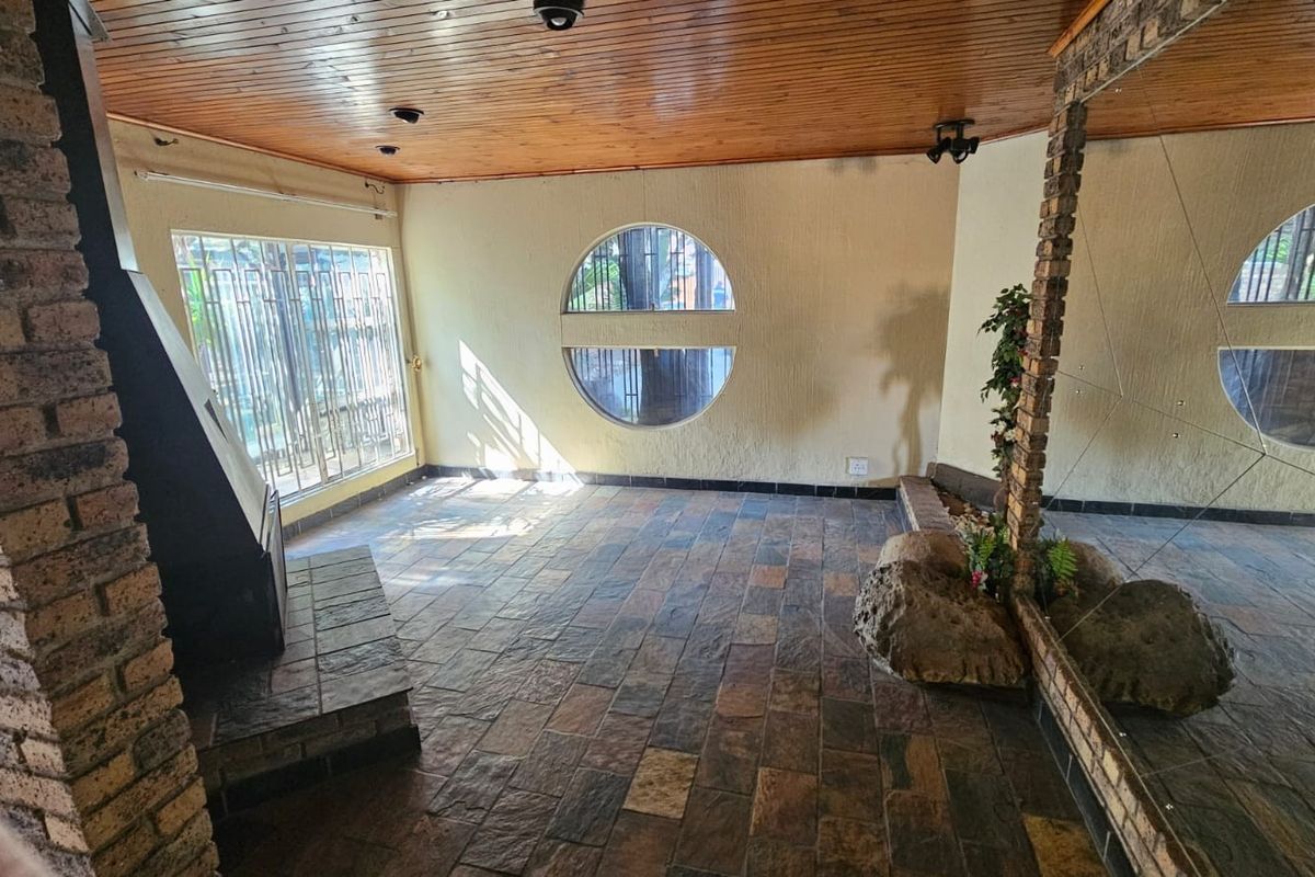 Spacious living area featuring a timber ceiling, slate tile flooring, a brick fireplace, and a unique circular window, offering a rustic aesthetic.