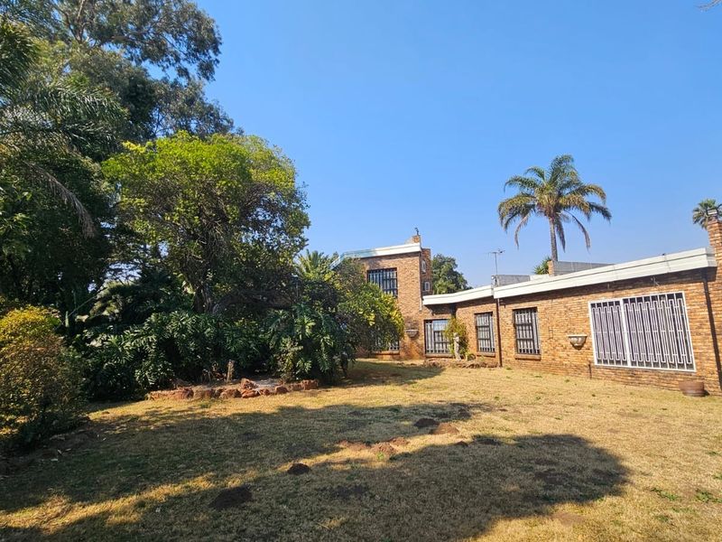 Rear view of a face brick house featuring established garden landscaping and security bars on the windows.